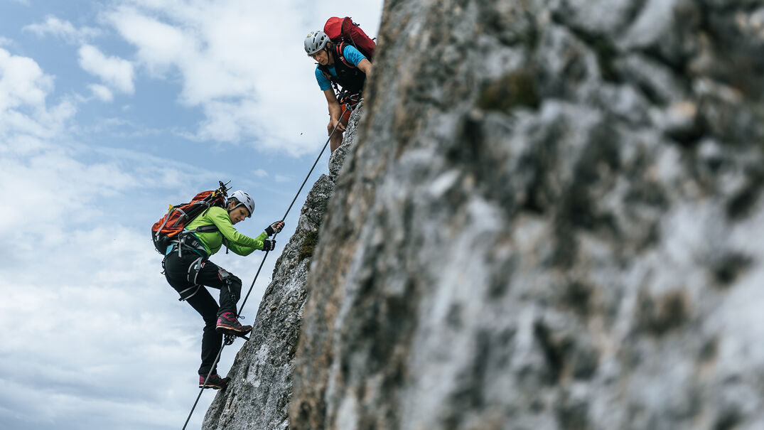 Klettersteiggehen im Rofangebirge am Achensee Ein Mann und eine Frau auf einem Klettersteig im Rofangebirge bei wenig bewölktem Himmel.