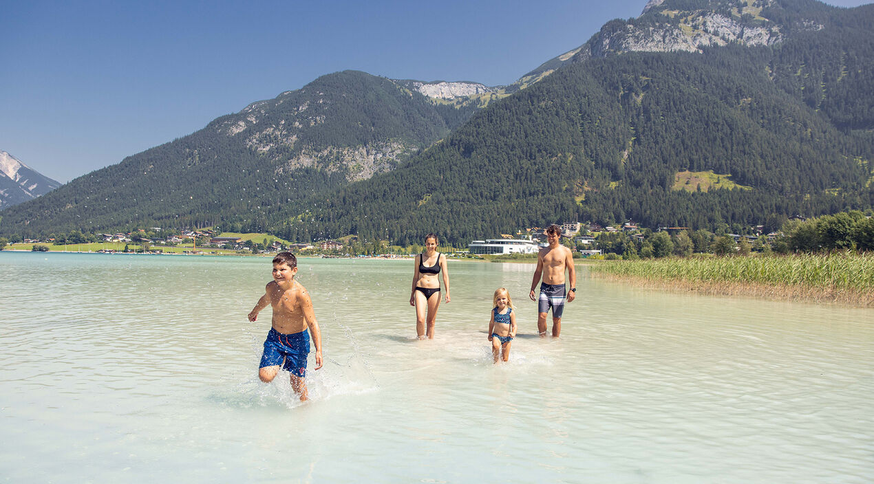 Badespaß mit der Familie in Maurach am Achensee Eine Familie genießt das schöne Wetter und badet im türkisblauen Achensee in Maurach.