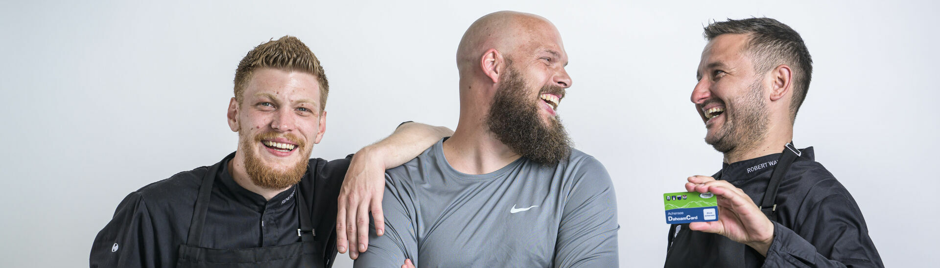 Achensee DahoamCard Zwei Köche und ein Fitnesstrainer posieren mit der Achensee DahoamCard vor einer weißen Wand.}