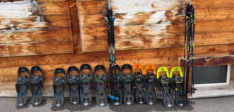 Schneeschuhe & Wanderstöcke an einer urigen Hüttenwand angelehnt