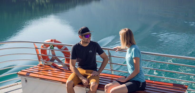 Ein Pärchen begibt sich auf einen Ausflug mit der Achenseeschifffahrt, um gemeinsam das Wasser und die malerische Landschaft in vollen Zügen zu genießen.