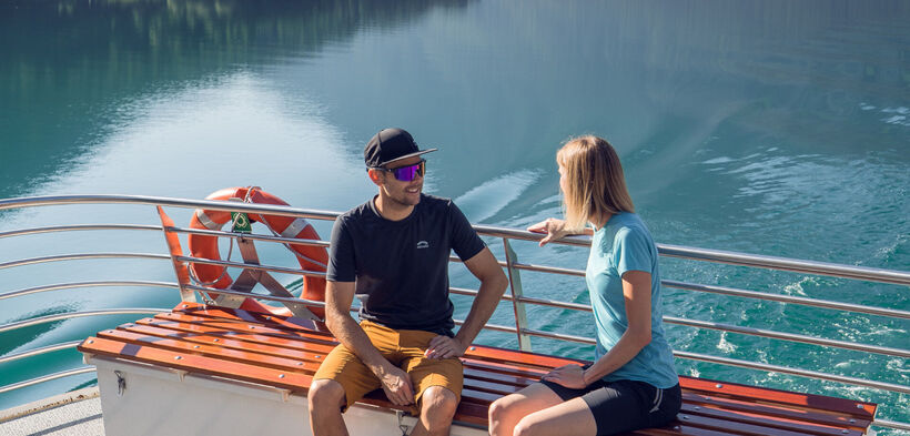A couple enjoying a boat trip with the Achenseeschifffahrt, enjoying the water and the beautiful natural surroundings.