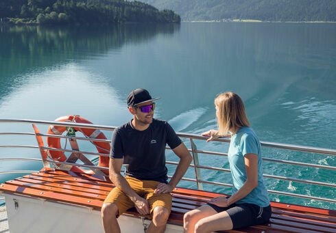 Ein Pärchen begibt sich auf einen Ausflug mit der Achenseeschifffahrt, um gemeinsam das Wasser und die malerische Landschaft in vollen Zügen zu genießen.