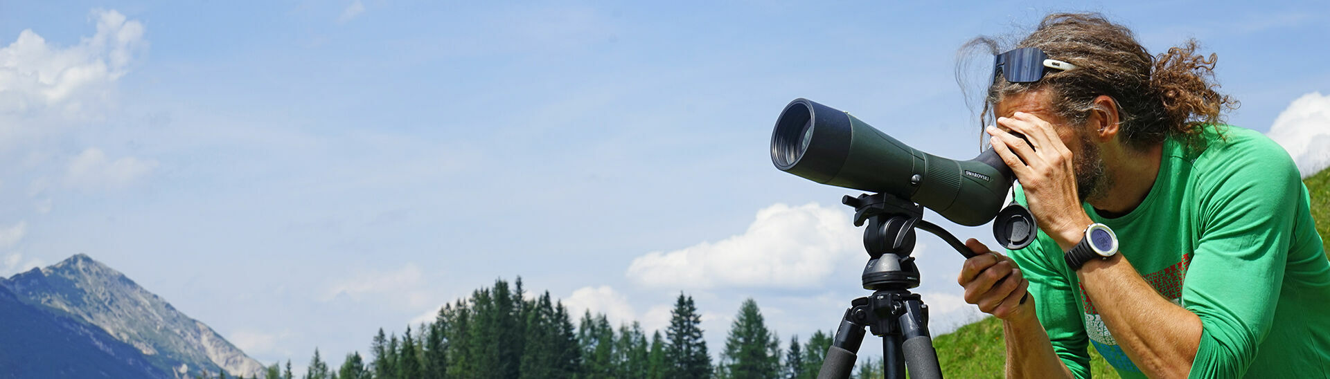 Steinadlerwanderung im Naturpark Karwendel Ein Mann schaut durch sein Teleskop einer Steinadlerwanderung im Naturpark Karwendel zu.}