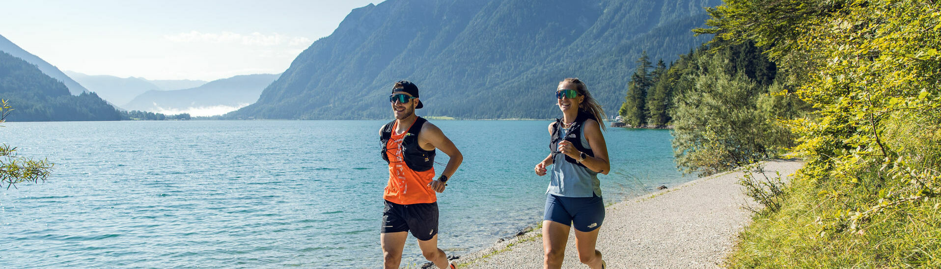 Zwei Läufer bei schönem Sommerwetter am Ufer des Achensees.}