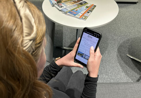 Eine Frau entdeckt den digitalen Urlaubsbegleiter my Achensee auf ihrem Handy.