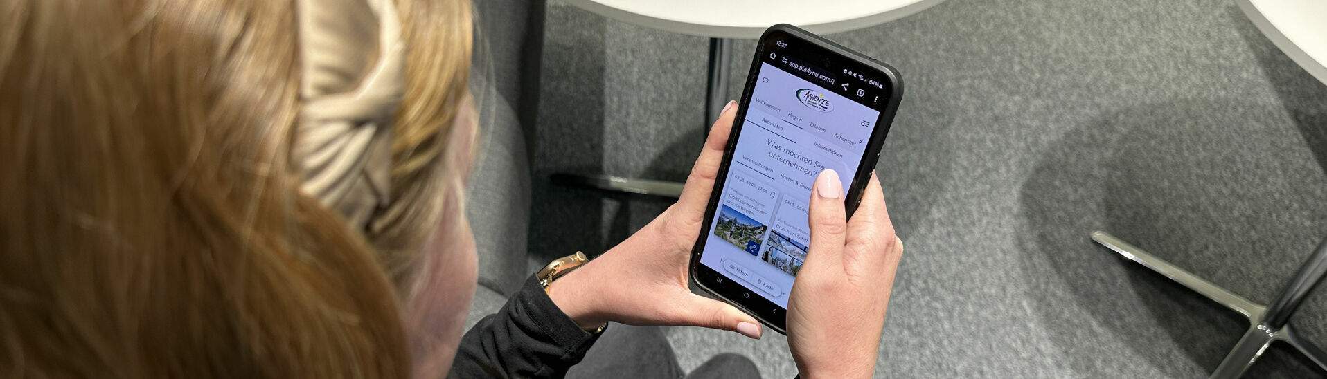 Eine Frau entdeckt den digitalen Urlaubsbegleiter my Achensee auf ihrem Handy.}