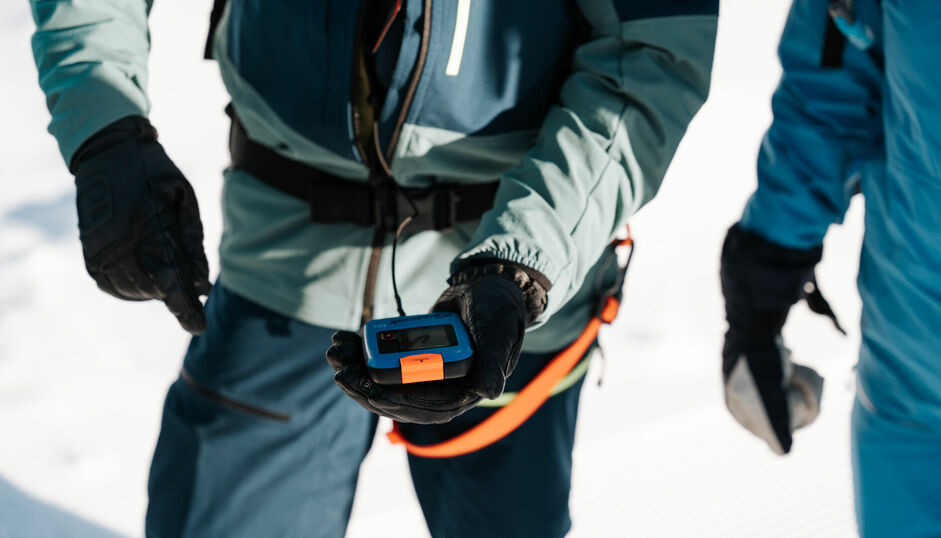 Ein Skitourengeher hält sein lebensrettendes Lawinenverschüttetensuchgerät (LVS) in der Hand.