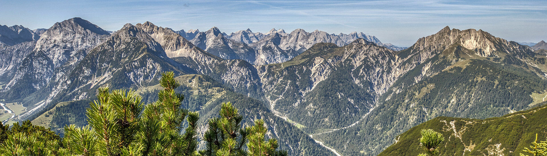 The mountain peaks of the Karwendel Nature Park tower upwards in the sunlight.}