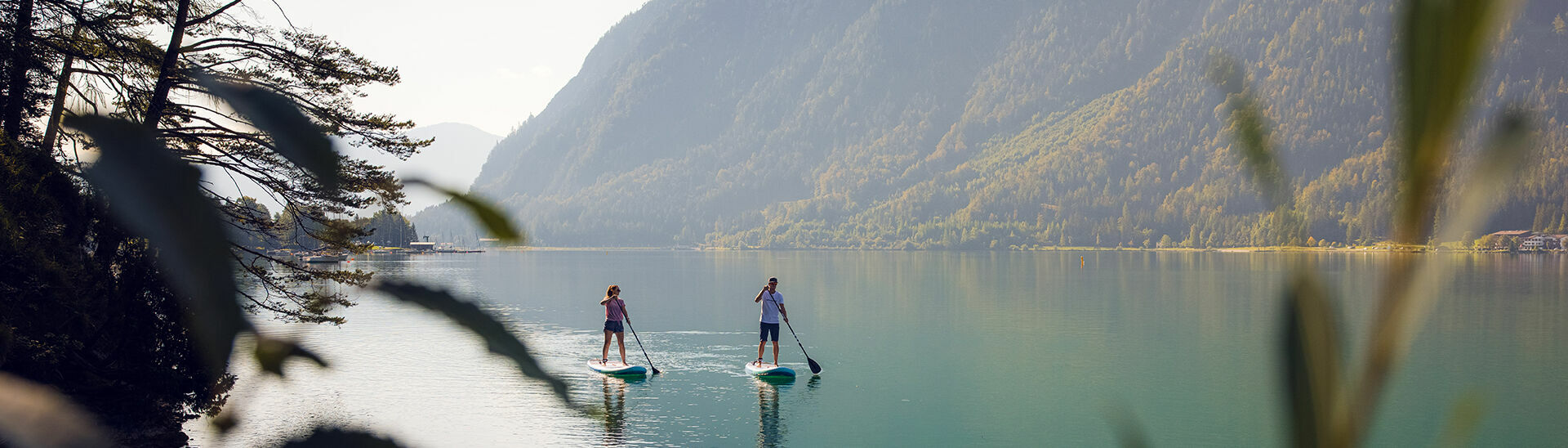 SUP am Achensee Mit einem großen, breiten Surfbrett und einem Paddel gleitet man entspannt über das Wasser des Achensees.}
