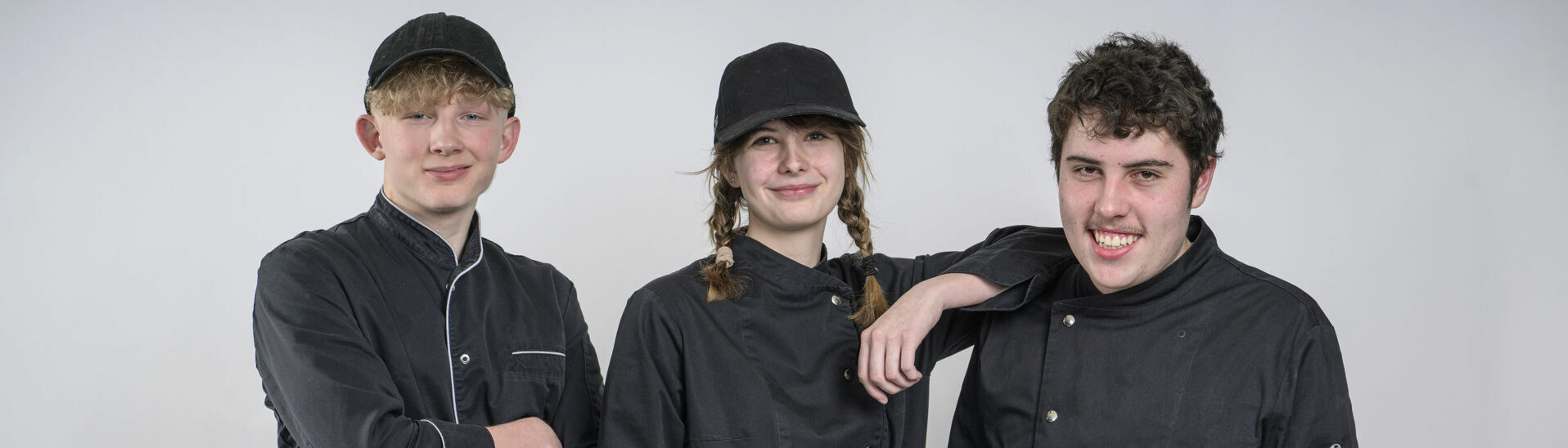 Lehrlinge am Achensee Zwei auszubildende Köche und eine Konditorin posieren vor einer weißen Wand.}