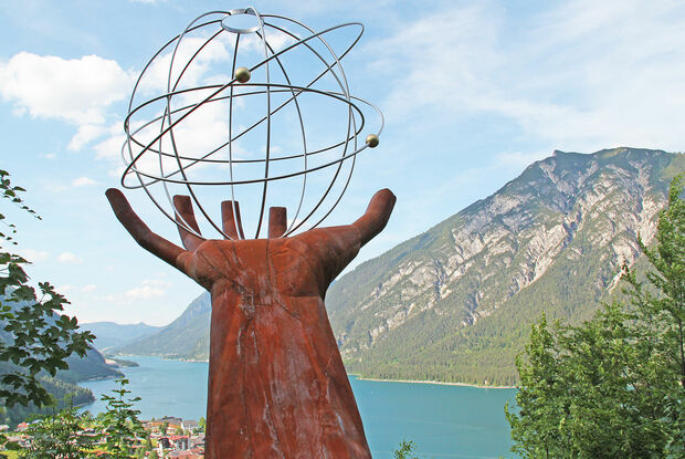Der Besinnungsweg in Pertisau am Achensee Eine Skulptur einer Hand die einen eisernen durchsichtigen Planeten auf dem Besinnungsweg am in Pertisau hält.