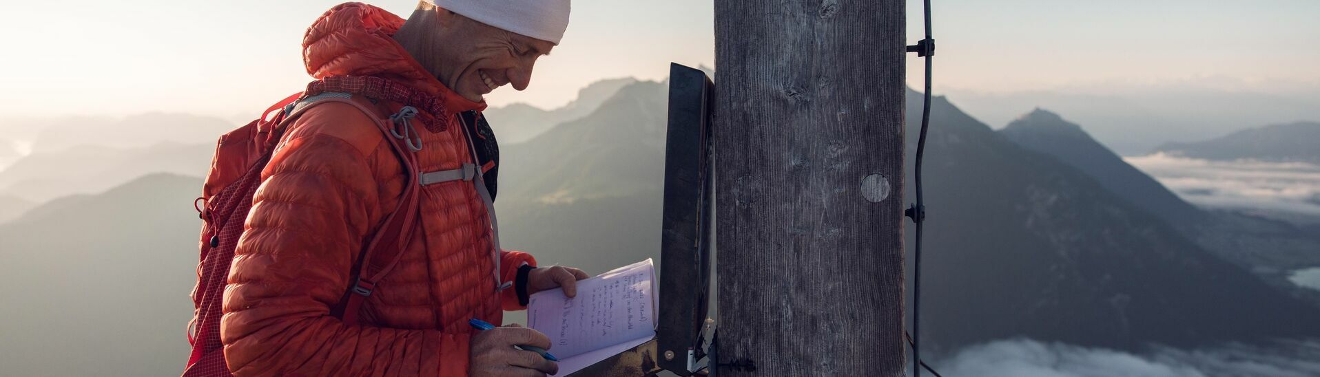 Gipfelbucheintrag auf der Seekarspitze im Karwendelgebirge Ein Bergläufer der sich im Gipfelbuch der Seekarspitze im Karwendelgebirge einträgt bei einer schönen Aussicht auf die nebeligen Täler.}