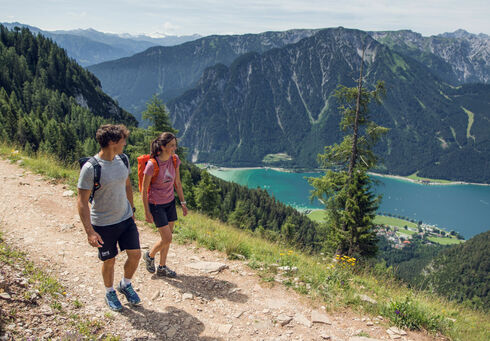A couple walks along a hiking trail in the Rofan Mountains enjoying the beautiful wildflower meadows.