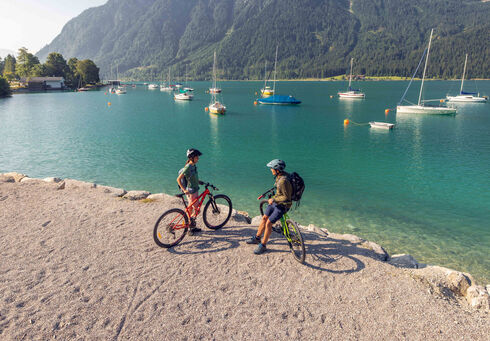 A couple explores the lakeshore in Maurach am Achensee by bike.