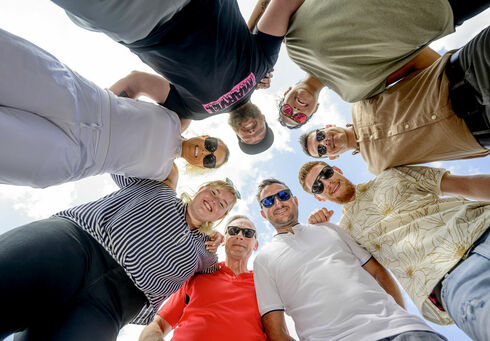 Ein Team an Frauen & Männern steckt die Köpfe zusammen.