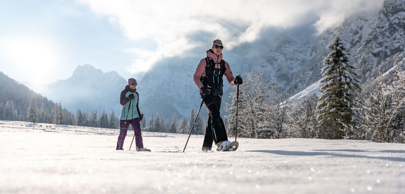 Zwei Freundinnen unternehmen bei herrlichem Wetter eine Schneeschuhwanderung im Falzthurntal im Naturpark Karwendel.