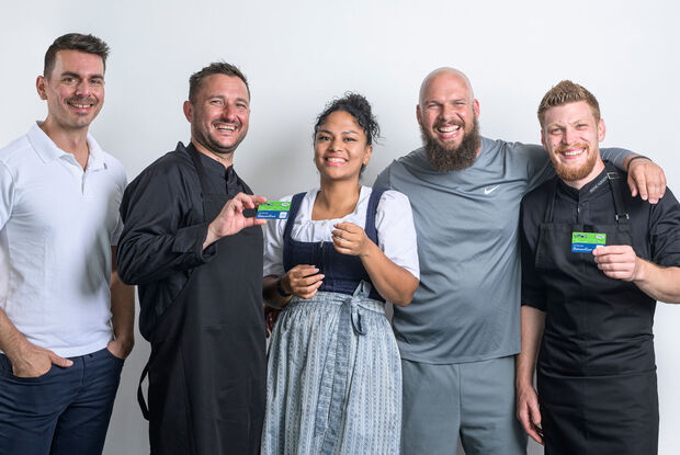 Mitarbeiter der Region Achensee Ein Masseur, ein Koch, eine Kellnerin, ein Fitnesstrainer und ein weiterer Koch posieren mit der Achensee DahoamCard.