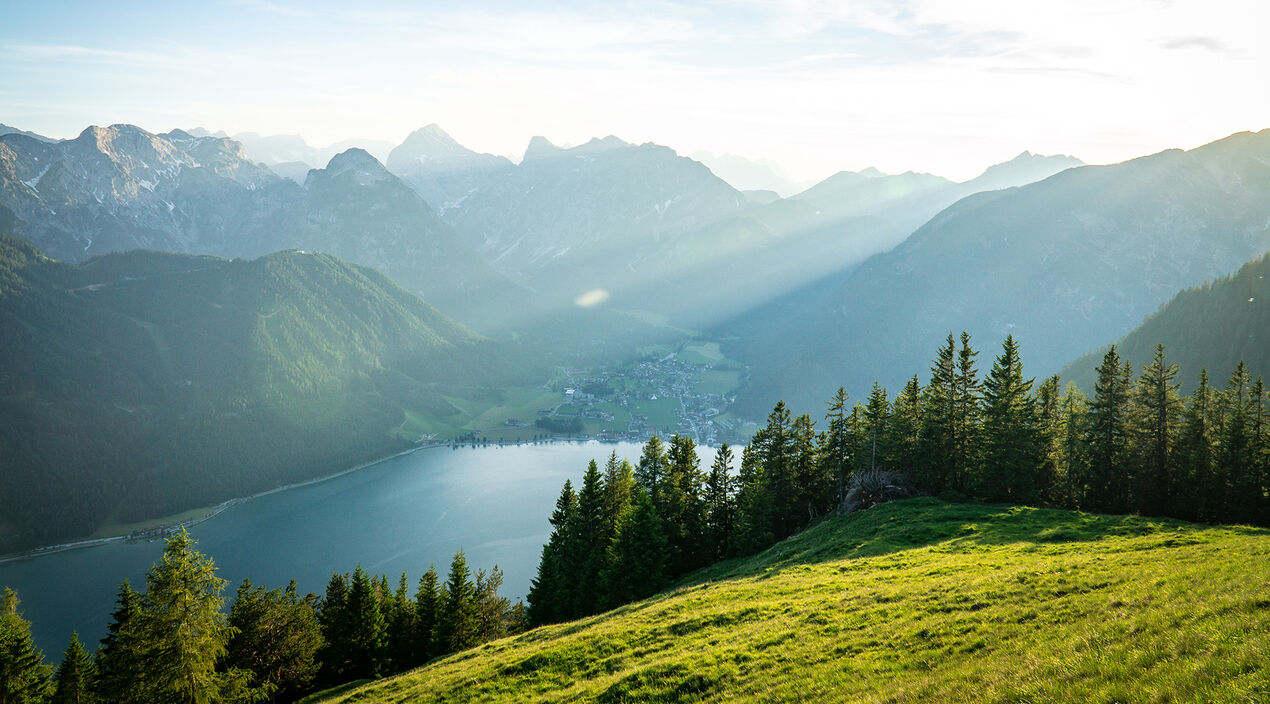 Die wiesenbedeckte Naturlandschaft des Rofangebirges mit Blick auf das Dörfchen Pertisau am Achensee.