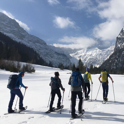 Schneeschuhwanderer sind gemeinsam in der Winterlandschaft am Achensee unterwegs.
