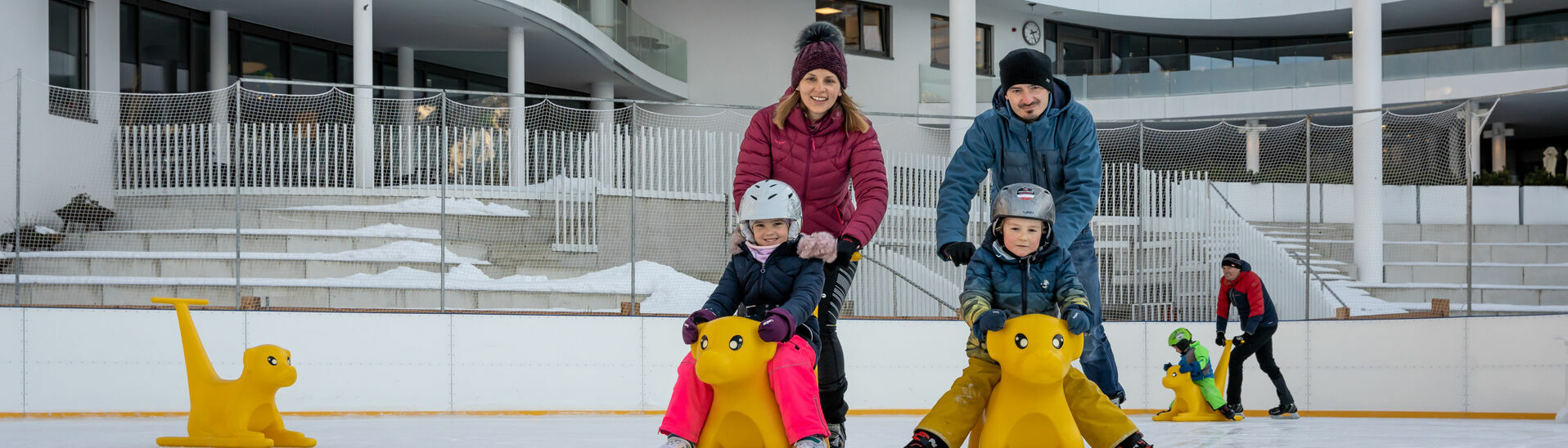 Eine Familie genießt den Wintertag auf dem Eislaufplatz des Atoll Achensee in Maurach.}