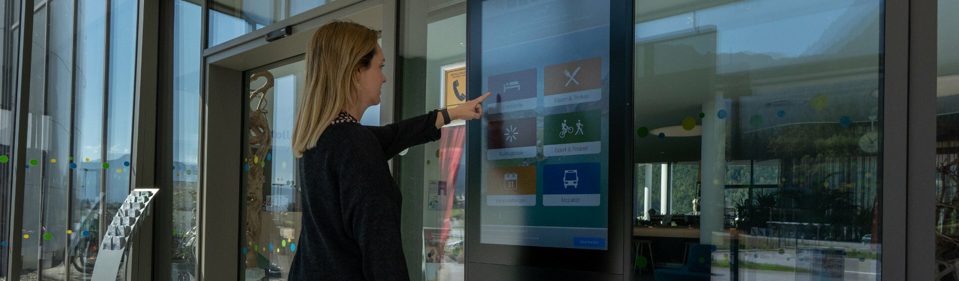 Eine Frau informiert sich am Infoterminal im Achensee Atoll über die Region Achensee.