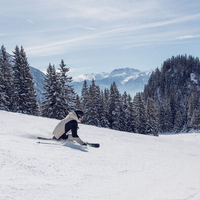 A skier enjoys the sunny winter day on the perfectly groomed slopes of the Rofan mountains overlooking the Nature Park Karwendel.
