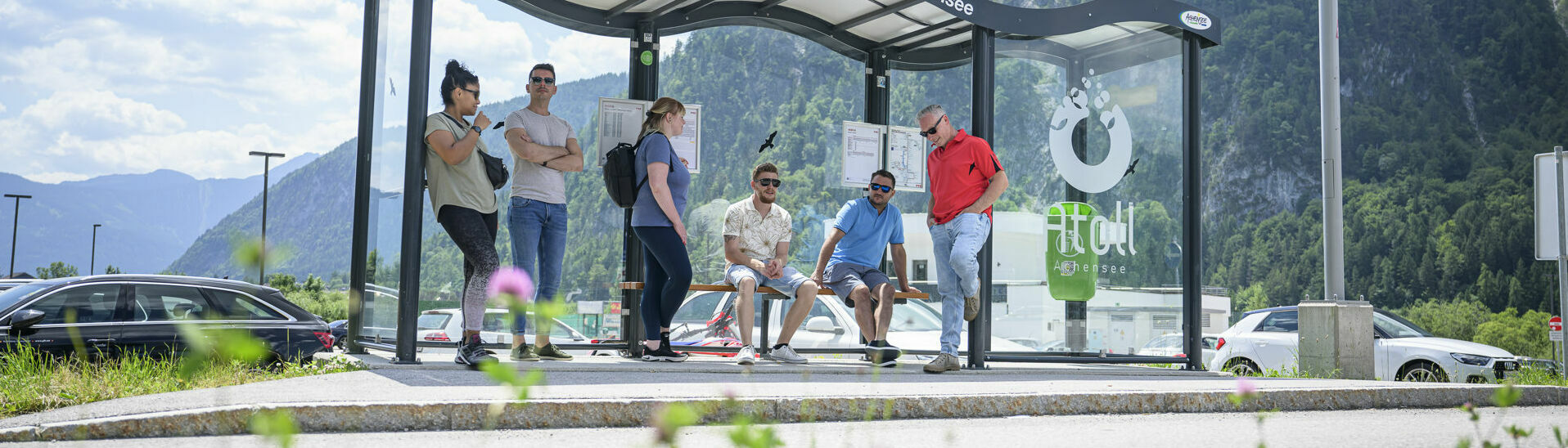 Bushaltestelle beim Atoll Achensee Eine Gruppe Männer und Frauen warten auf den nächsten Bus bei der Haltestelle des Atoll Achensee.}