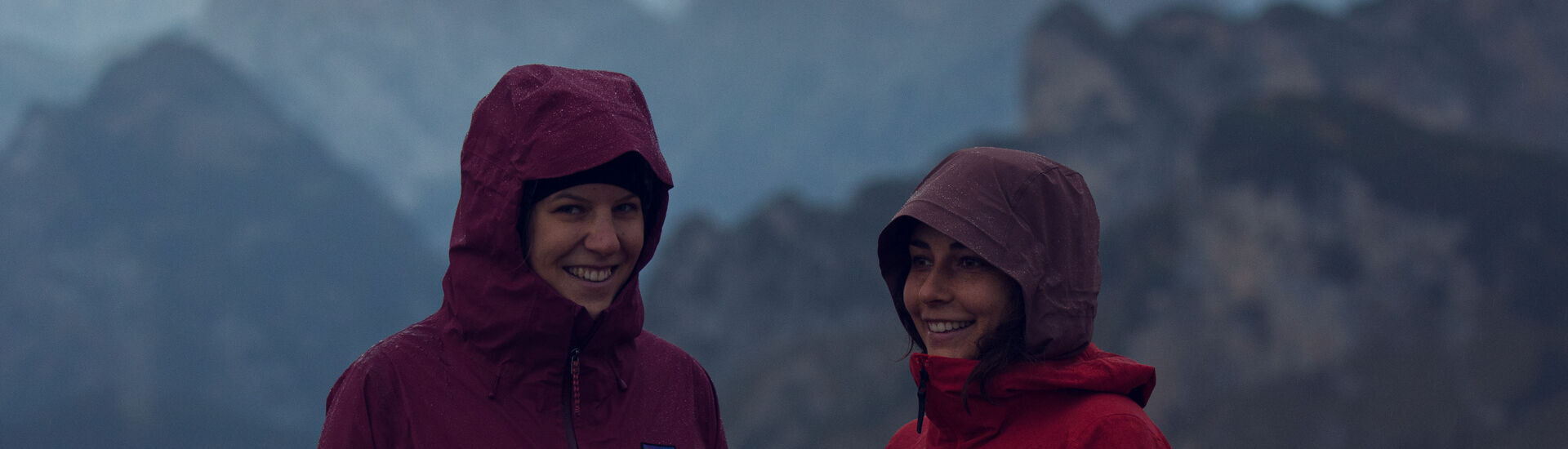 Zwei junge Frauen wandern gut ausgerüstet bei trübem Wetter im Rofangebirge.}