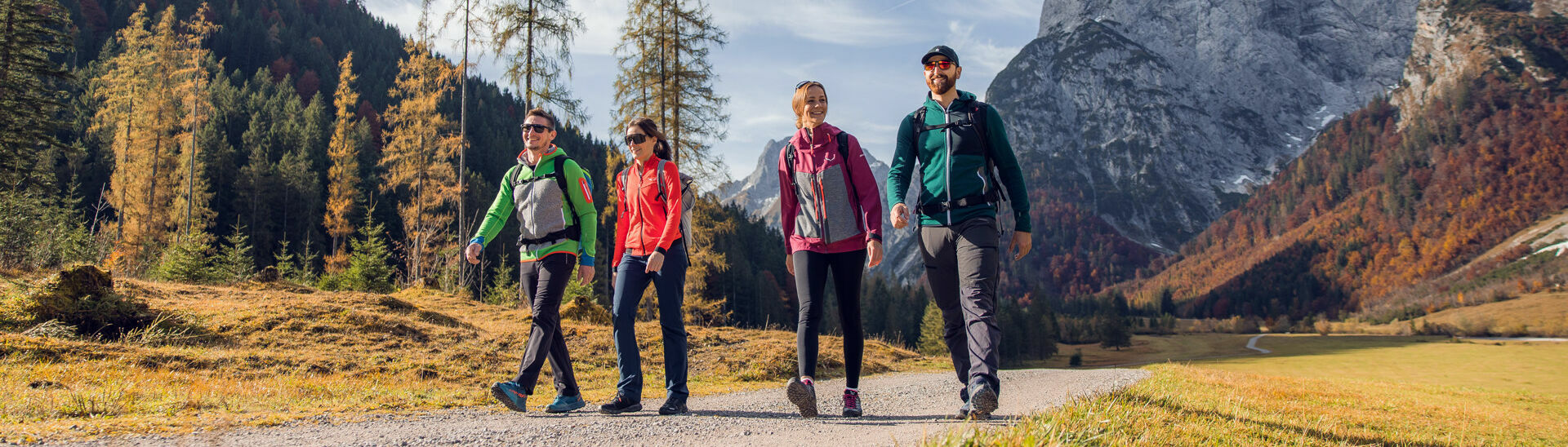 Eine Gruppe von Freunden nutzt das schöne Wetter für eine Herbstwanderung durch das bunt gefärbte Falzthurntal im Naturpark Karwendel.}