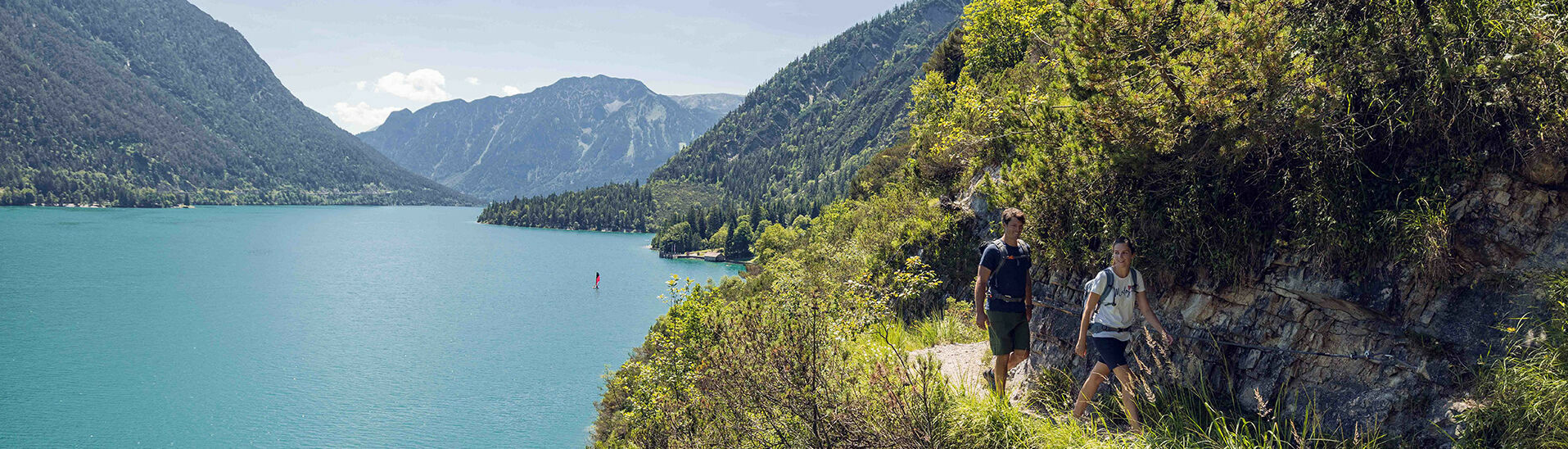 Pärchen-Wanderung am Gaisalmsteig Ein Mann und eine Frau wandern am Gaisalmsteig neben dem Türkisen Achensee bei blauem Himmel.}
