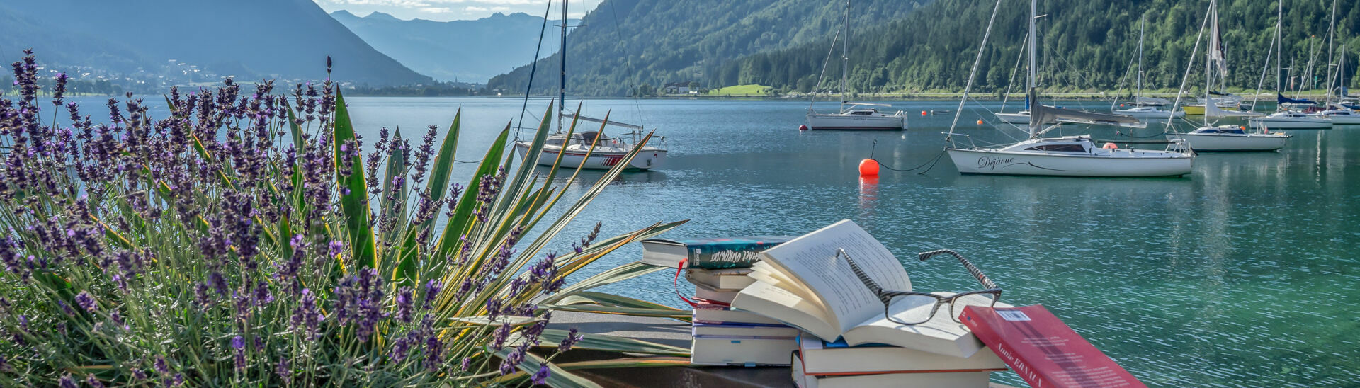 achensee.literatour Im Zuge des Literaturfestivals „achensee.literatour“ wurden viele fesselnde Bücher vor einer atemberaubenden Kulisse in Szene gesetzt, begleitet vom malerischen Achensee, Segelbooten und dem majestätischen Ebner Joch im Hintergrund.}