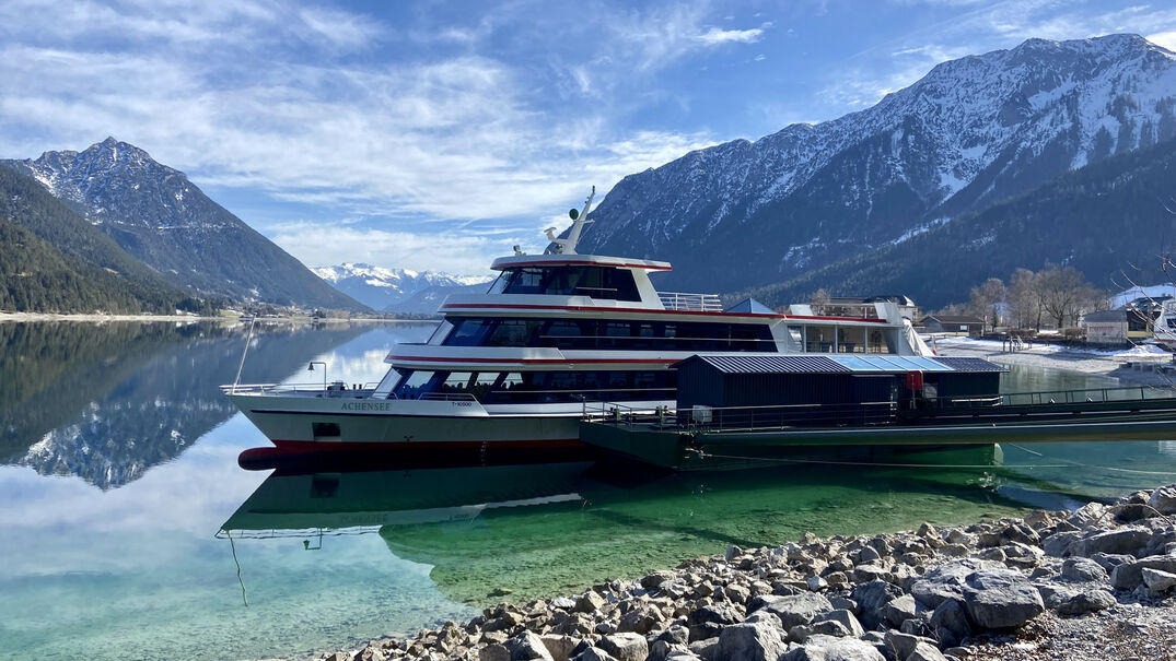 Die Achenseeschifffahrt in Pertisau am Achensee Die Achenseeschifffahrt legt hier in Pertisau am Achensee an. Im Hintergrund sind angezuckerte Berge wie das Ebner Joch zu sehen.