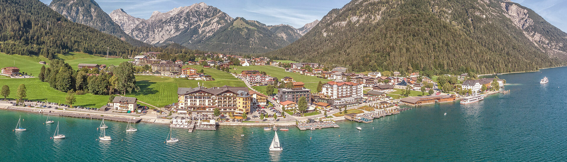 Pertisau am Fuße des Naturpark Karwendel begeistert mit seiner wunderschönen Landschaft. Am Ufer können Segelboote bewundert werden. }